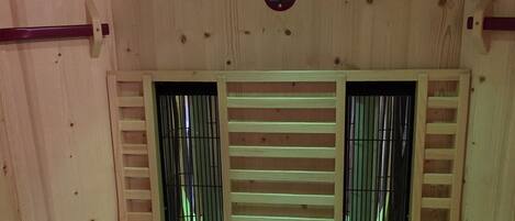 A wooden interior with a central ventilation system and two windows with metal bars.