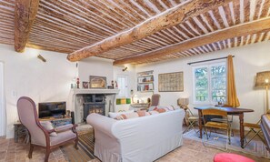 A cozy living room with a fireplace, comfortable seating, and a dining area. - Maison La louvegine | House in the Heart of Vaugines (Vaugines)