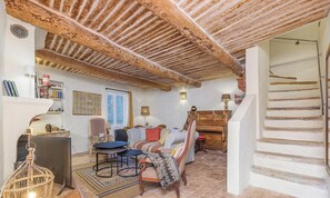 A cozy living room with a fireplace, a staircase, and a view of the outdoors. - Maison La louvegine | House in the Heart of Vaugines (Vaugines)