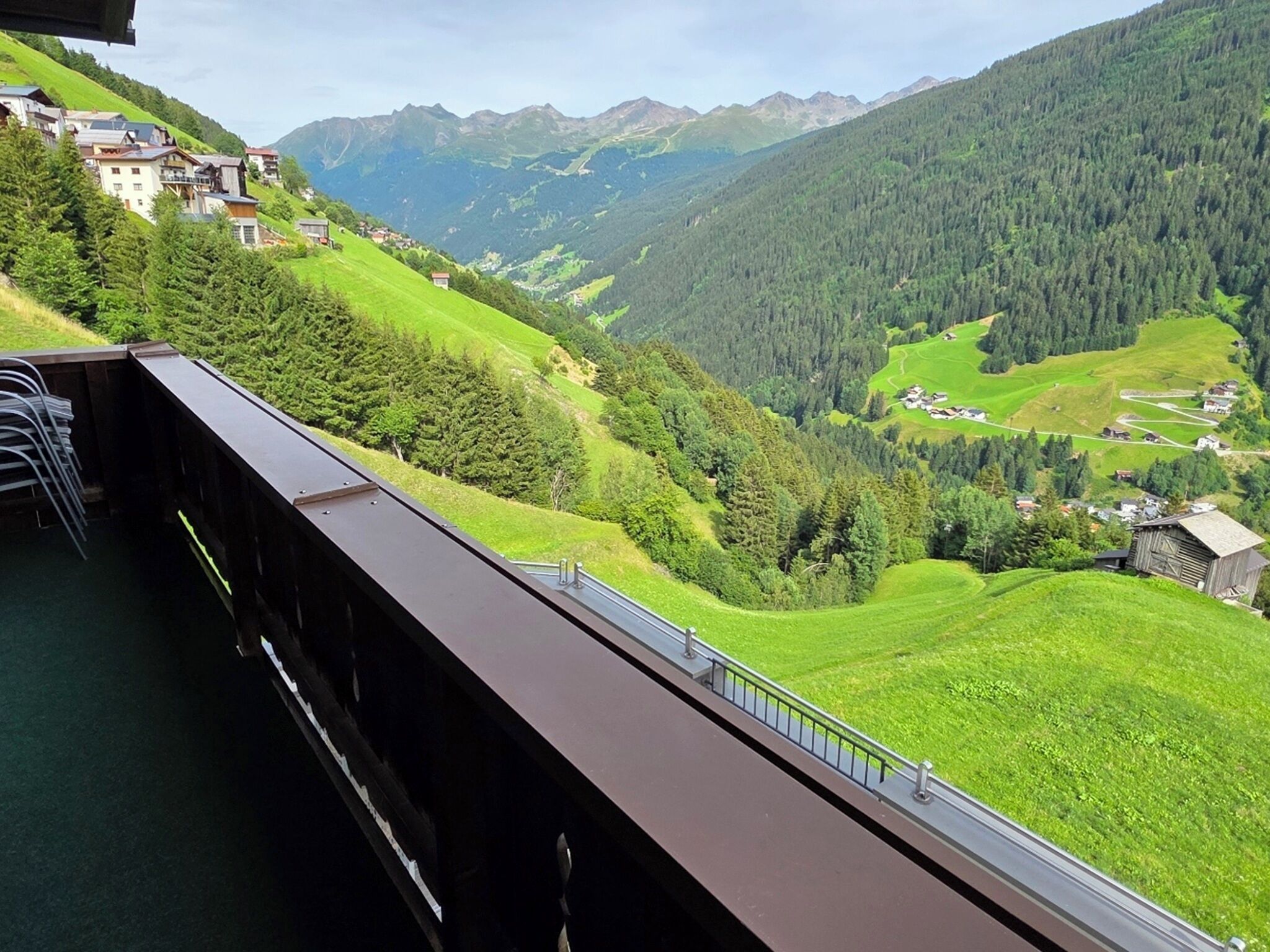 A scenic view from a bridge overlooking a valley with houses and mountains in the background.