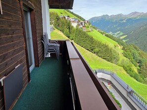 A balcony with a view of a mountainous landscape, wooden exterior walls, and outdoor furniture. - Stylishly renovated and panoramic view (Kappl)