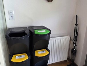 Two waste bins with labels for paper and metal, and a vacuum cleaner in the background. - Stylishly renovated and panoramic view (Kappl)