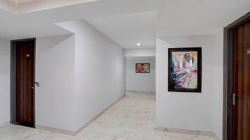 Un pasillo con paredes blancas, una puerta de madera a la izquierda y un cuadro enmarcado a la derecha.