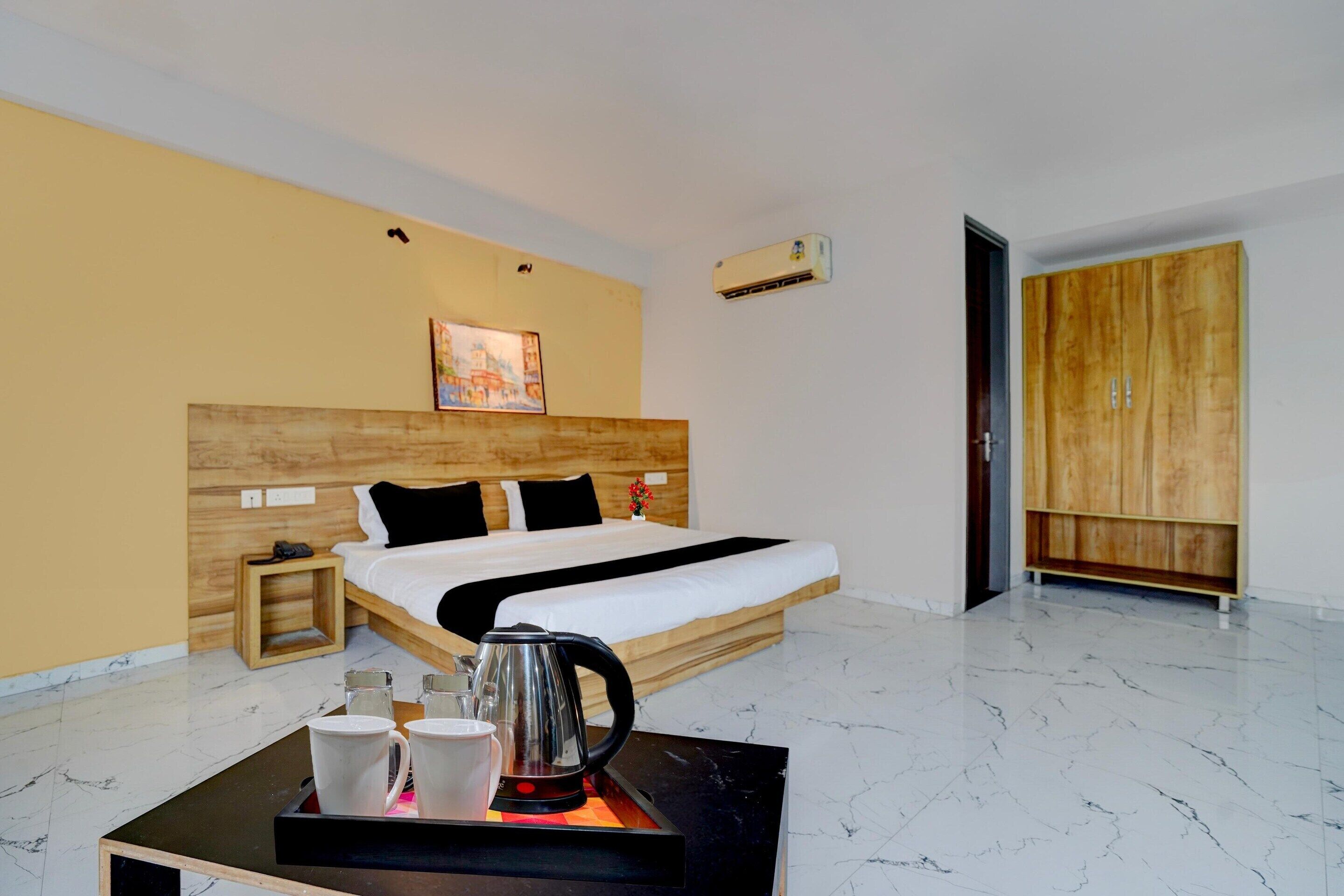 A hotel room with a bed, bedside table, and a coffee table with cups and a kettle.