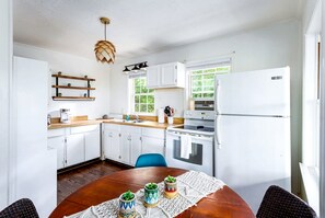 A modern kitchen with white cabinets, a wooden countertop, a stove, and a refrigerator. - Cozy Cottage with Hot Tub, Fire Pit and Sunroom - Loaded with Modern Touches in Front Royal, VA (Front Royal)