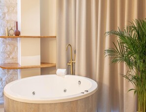 Ein modernes Badezimmer mit freistehender Badewanne, Handtuchhalter und einer Topfpflanze.