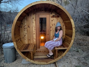 Eine Holzsauna mit Sitzbank und Tür, eingebettet in eine natürliche Landschaft.