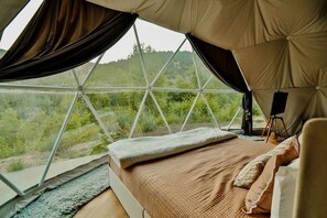 Eine Zeltoase mit Bett, Blick ins Grün und Staffelei.