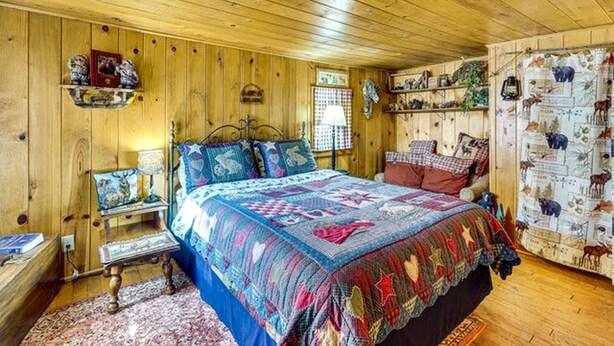 Camera da letto in una baita di legno, con un letto, comodini e una finestra.