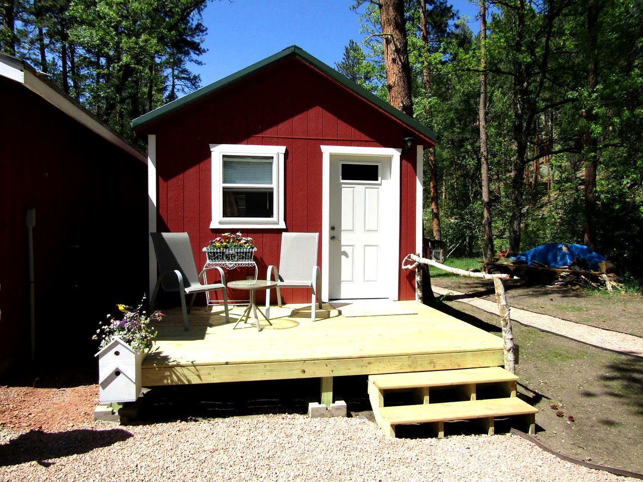 A red cabin with a wooden deck, a door, and a window.