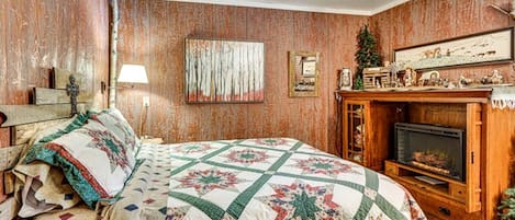Un dormitorio con una cama grande, una chimenea y paneles de madera en las paredes.