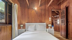 Een houten kamer met een bed, nachtkastjes en een deur.