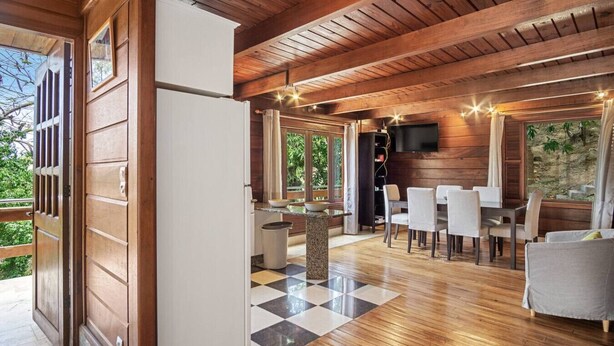 Een houten interieur met een eetgedeelte, een keuken en een aan de muur bevestigde televisie.