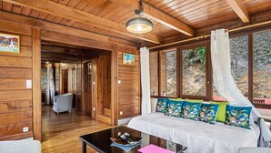 Een houten interieur met een bed, een glazen bijzettafeltje en uitzicht op het groen.