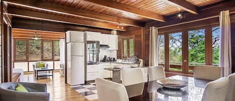 A spacious kitchen with modern appliances, a dining area with a large table and chairs, and large windows offering a view of the outdoors.