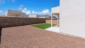 A modern outdoor area with a stone wall, gravel ground, and a grassy patch.
