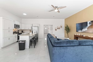 A modern kitchen with white cabinets, a central island, and a ceiling fan.