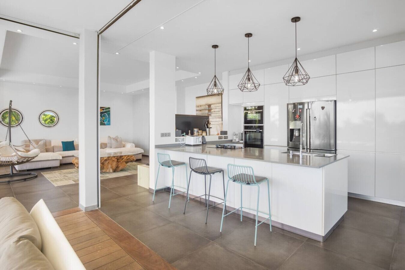 Una cocina moderna con una isla central, taburetes de bar y electrodomésticos de acero inoxidable.