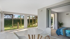 A modern room with a balcony, a round table, two chairs, and a bed with a blue patterned bedspread. - Villa El Desert, right on the water (Sainte-Luce)