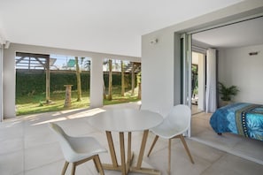 Ein modernes Zimmer mit Balkon, einem runden Tisch, zwei Stühlen und einem Bett mit blauem Muster.