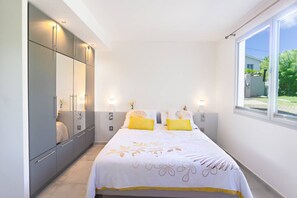 Een slaapkamer met een bed, nachtlampjes, een kledingkast en een raam.