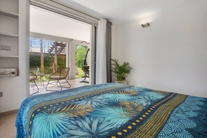Ein Schlafzimmer mit einem großen Bett, einer Schiebetür zum Balkon und einem kleinen Tisch mit Stühlen.