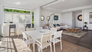 A modern living space with a dining area, a sofa, and a hanging chair. - Villa El Desert, right on the water (Sainte-Luce)