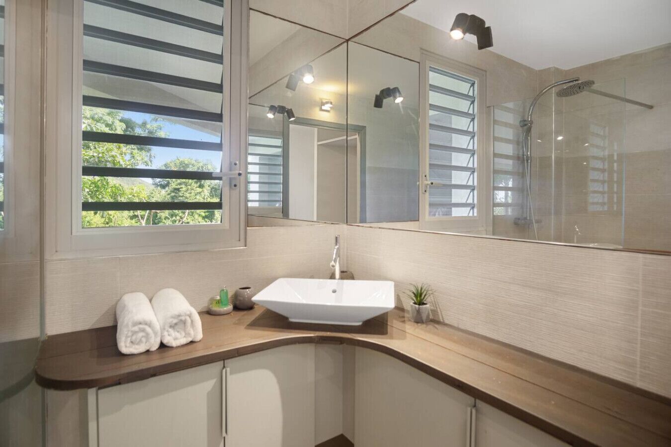 A modern bathroom with a large mirror, a sink, and a shower.