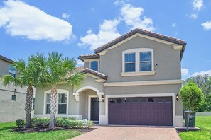 A two-story house with a garage, a palm tree, and a clear blue sky. - Bengal Court Reserve (Kissimmee)