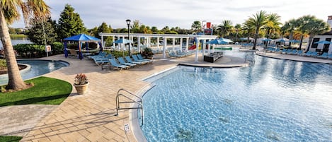 A pool area with lounge chairs, umbrellas, and a water slide.
