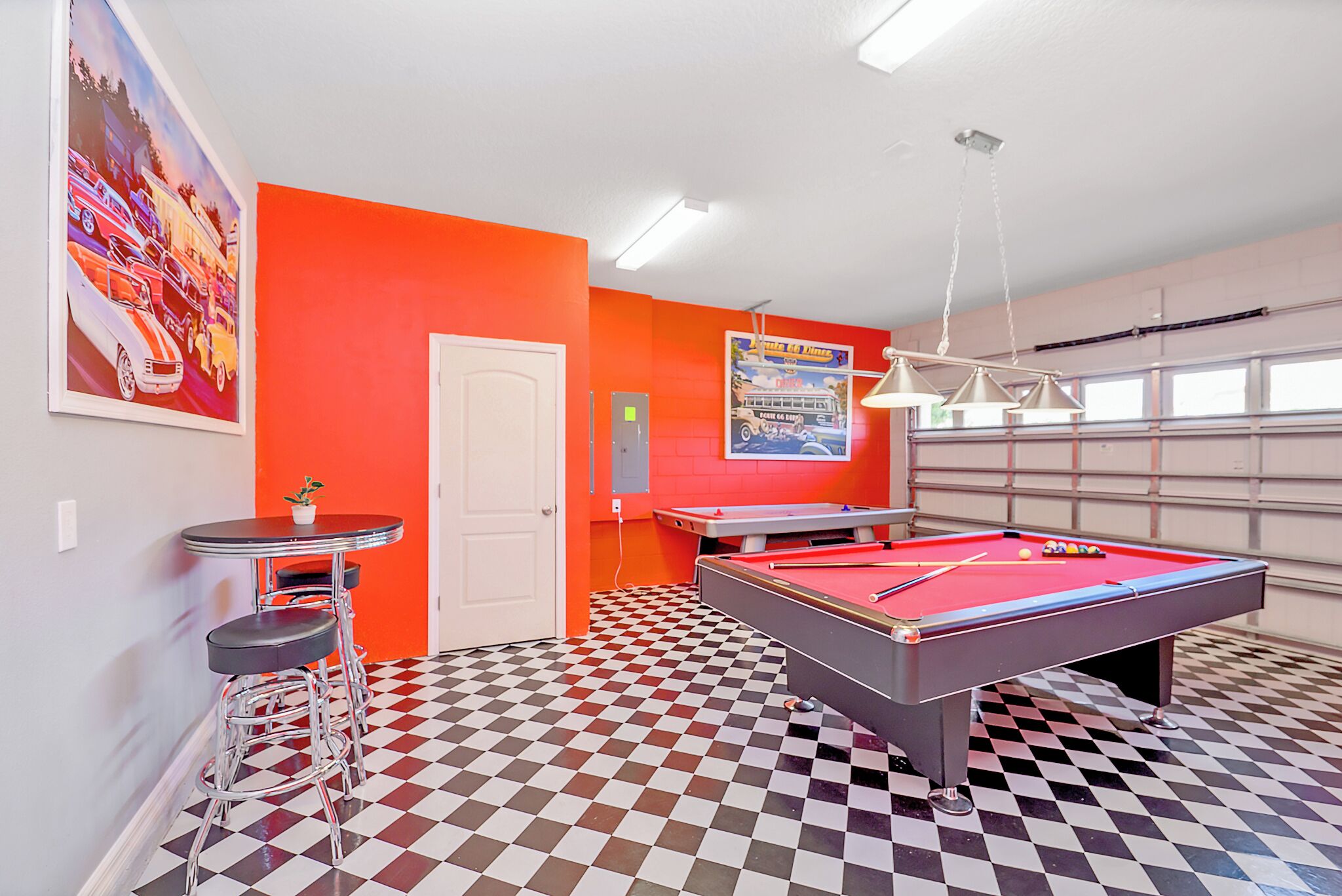 A room with a pool table, a bar area, and a checkered floor.