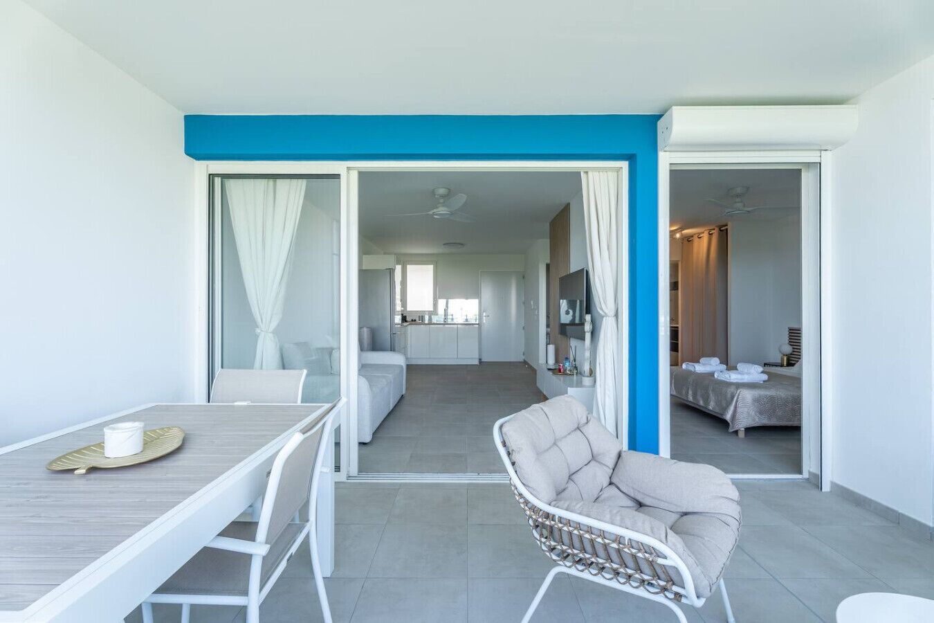 A modern hotel room with a dining area, a kitchenette, and a bathroom.
