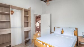 A bedroom with a wooden bed, a wardrobe, and a staircase leading to an upper floor.