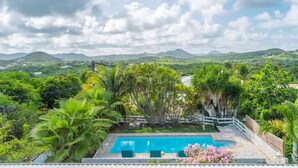 A swimming pool surrounded by lush greenery and a mountainous landscape in the background.
