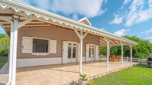 A covered patio area with a tiled floor, white doors, and a seating arrangement.