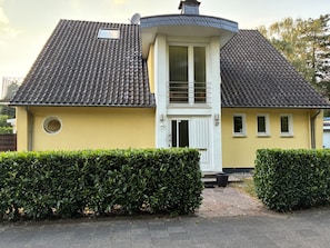 A two-story house with a tiled roof, a small balcony, and a door with a window.