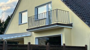 Et toetagers hus med balkon, tr æhegn og tegltag.