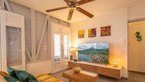 A living room with a sofa, a coffee table, a TV, and a ceiling fan.