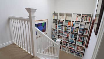 Una escalera con balaustres blancos que conduce a un rellano alfombrado.