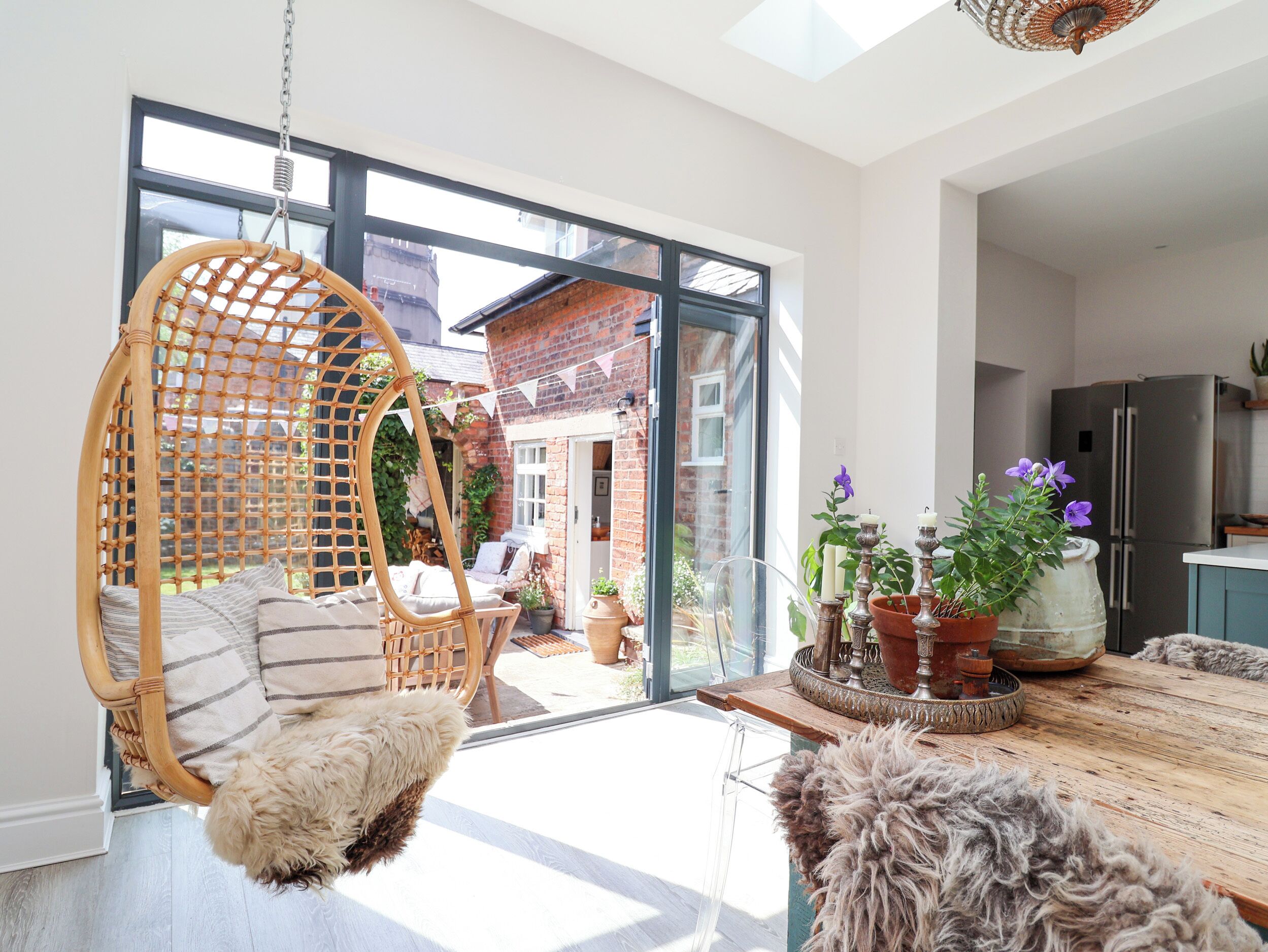 Un interior moderno con una silla colgante, una mesa de comedor con alfombra y una zona de cocina.