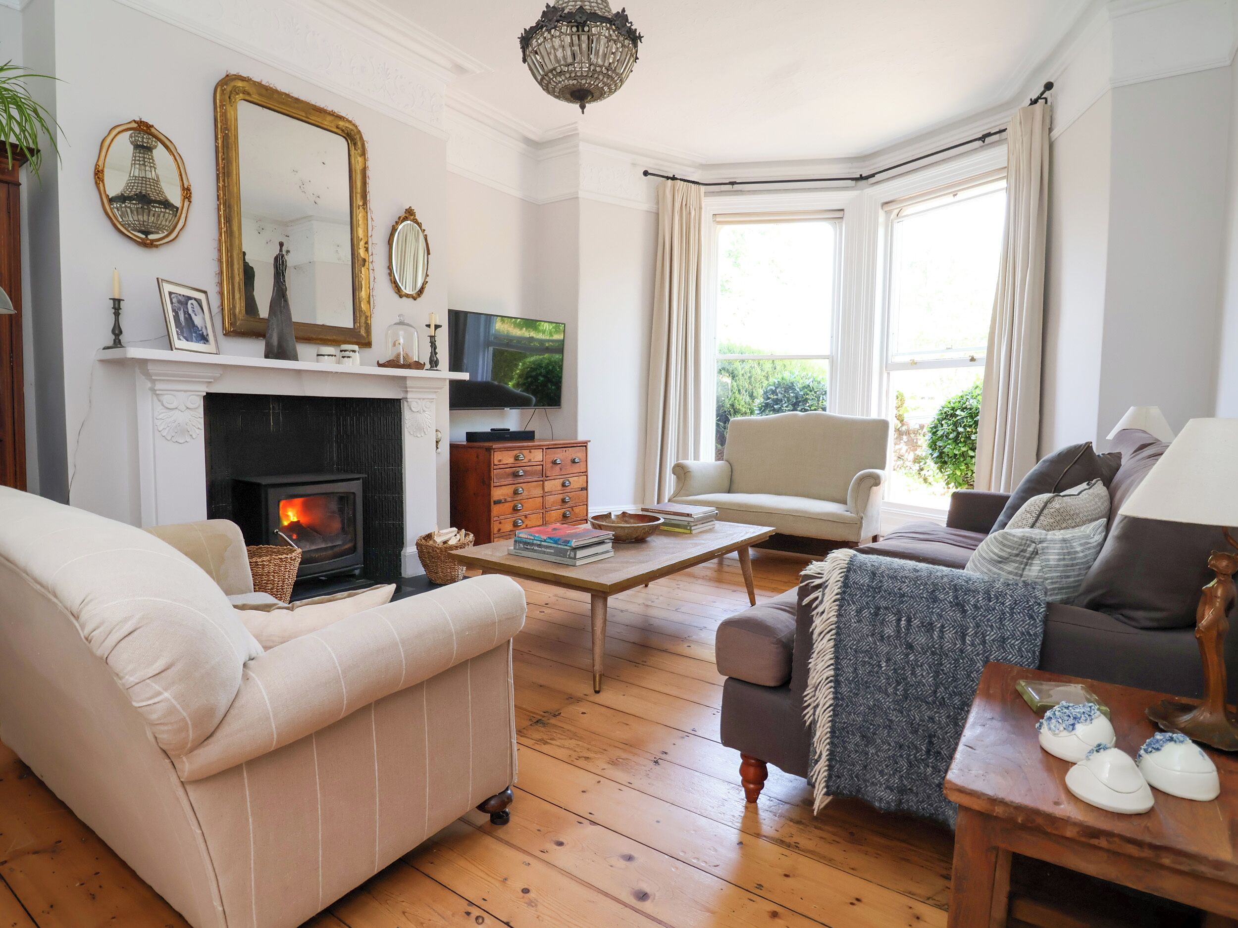 A living room with a fireplace, a television, and a large window with curtains.