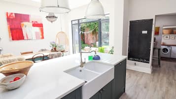 A modern kitchen with a large island, pendant lights, and a view of the garden.