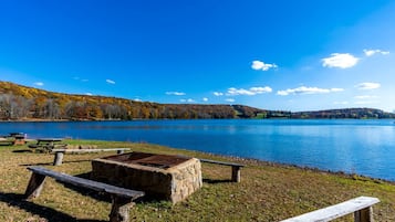 Uma área de piquenique à beira do lago, com bancos e mesas.