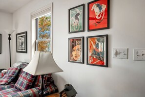 Ein Zimmer mit einem Bett, einer Lampe und vier gerahmten Postern an der Wand.