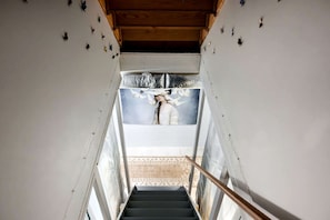 A staircase with a view of a room featuring a mural and a patterned floor. - Awesome Wooden Cabin with Fire Pit in Great Cacapon, West Virginia (Great Cacapon)
