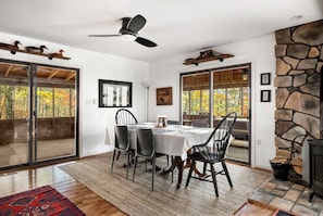 Uma sala de jantar com uma mesa posta para quatro pessoas, um ventilador de teto e uma parede de pedra.