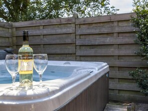A hot tub with two glasses and a bottle of wine. - Charming farm with sauna and hot tub (Balkbrug)