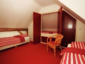 A dormitory room with two single beds, a chair, and a wardrobe. - Charming farm with sauna and hot tub (Balkbrug)