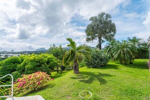 A lush garden with various tropical plants and a prominent palm tree. - Villa Blue Rock, Pool & Stunning View (Rivière-Salée)