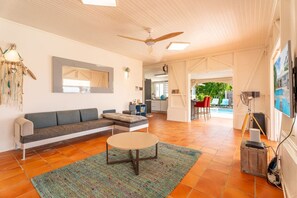 A modern living room with a sofa, a coffee table, and a ceiling fan. - Villa Blue Rock, Pool & Stunning View (Rivière-Salée)